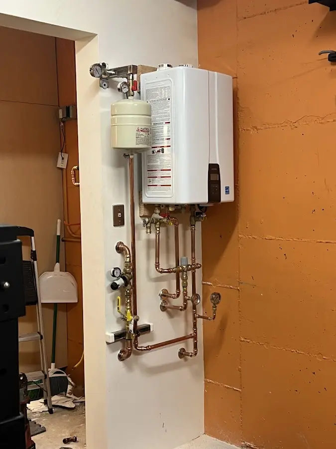 Plumbing technician inspecting water heater connections in Falcon Heights